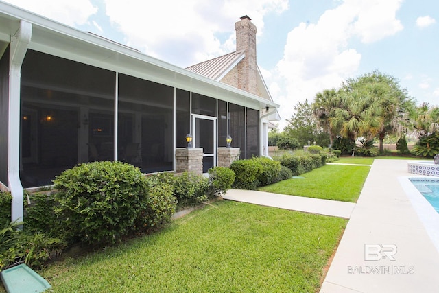 view of side of home with a sunroom and a lawn