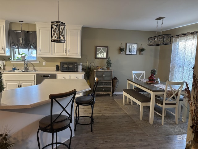 kitchen featuring dishwasher, dark wood-type flooring, white cabinets, sink, and hanging light fixtures