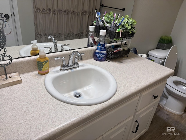 bathroom with hardwood / wood-style floors, vanity, and toilet