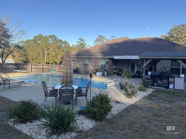 view of swimming pool featuring a patio area and a diving board