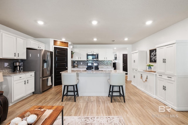 2526 E Windmere Dr, Semmes, AL 36575 - kitchen featuring appliances with stainless steel finishes, tasteful backsplash, a breakfast bar area, white cabinetry, and recessed lighting