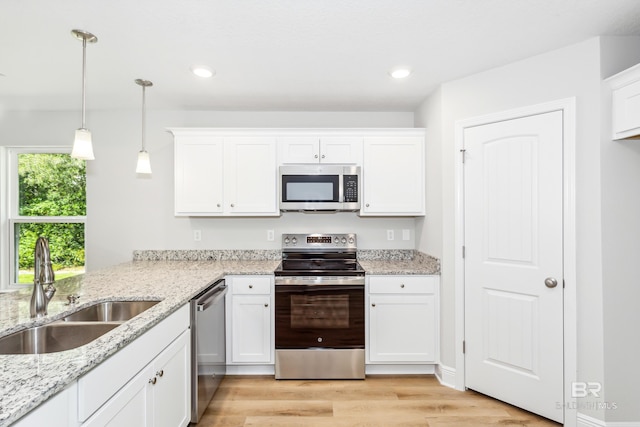 kitchen with white cabinetry, sink, light hardwood / wood-style floors, decorative light fixtures, and appliances with stainless steel finishes