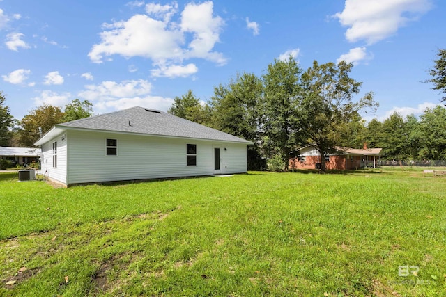 rear view of house featuring cooling unit and a yard