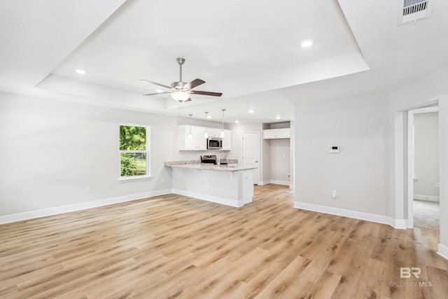 unfurnished living room with a raised ceiling, light hardwood / wood-style flooring, and ceiling fan