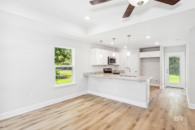 kitchen featuring white cabinetry, a wealth of natural light, kitchen peninsula, pendant lighting, and appliances with stainless steel finishes