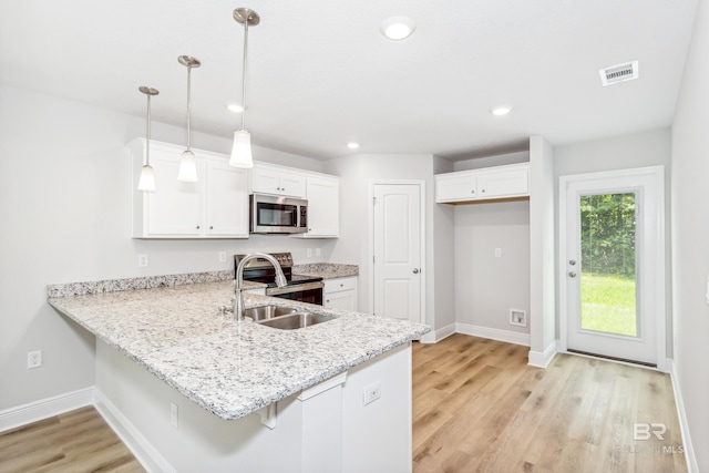 kitchen with pendant lighting, white cabinetry, stainless steel appliances, and light hardwood / wood-style flooring