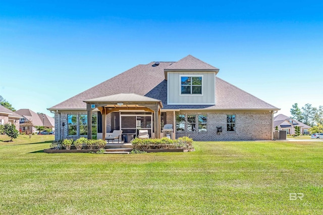 rear view of house with brick siding, a gazebo, central AC unit, and a yard