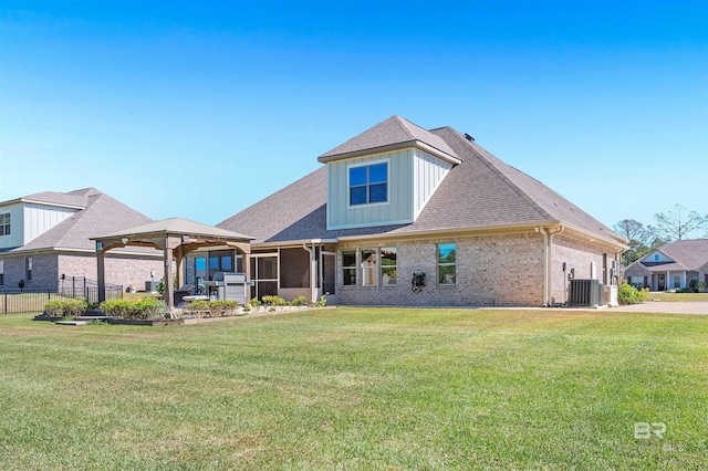 rear view of property featuring fence, cooling unit, board and batten siding, a lawn, and brick siding