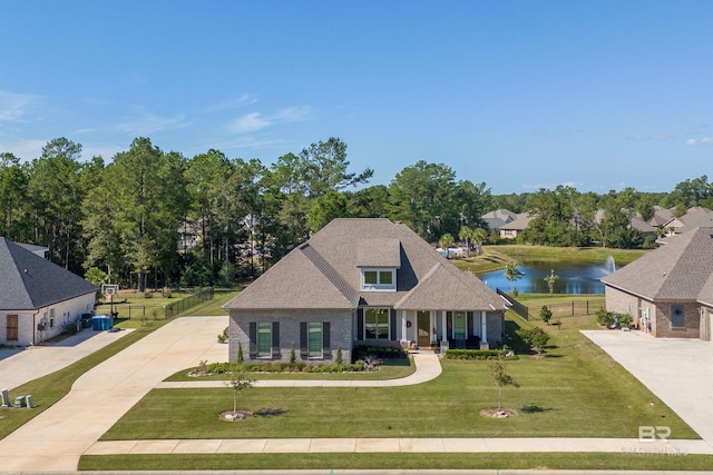 view of front of house featuring a front yard, a water view, driveway, brick siding, and fence