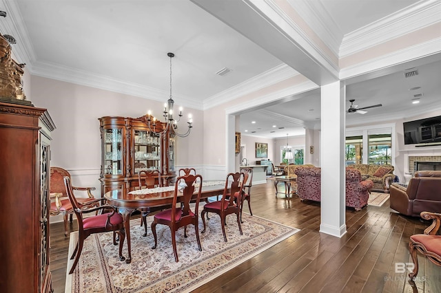 dining area featuring a fireplace, visible vents, a wainscoted wall, and ceiling fan with notable chandelier