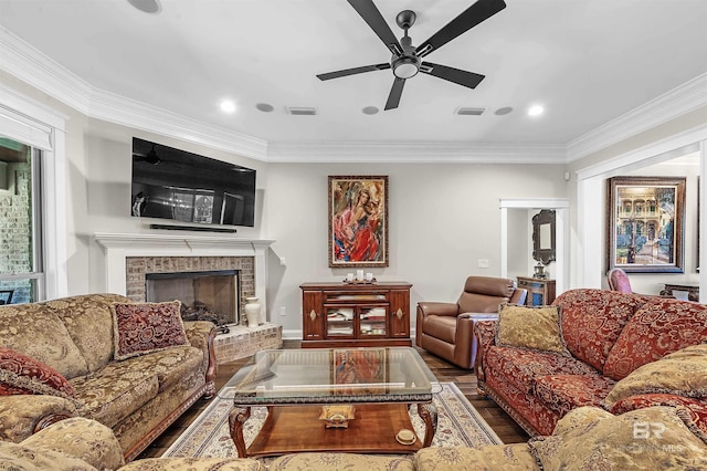living area featuring crown molding, ceiling fan, wood finished floors, and a fireplace