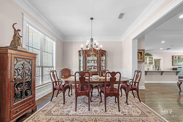 dining space with ornamental molding, visible vents, a chandelier, and dark wood finished floors