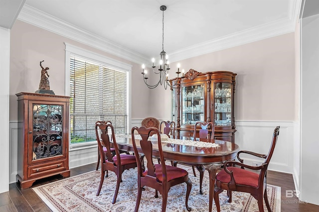 dining space with a chandelier, dark wood-type flooring, crown molding, a wainscoted wall, and a decorative wall