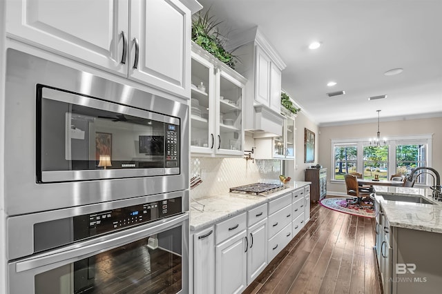 kitchen with dark wood-style floors, stainless steel appliances, white cabinetry, and a sink