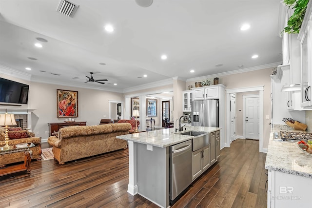 kitchen with appliances with stainless steel finishes, open floor plan, dark wood finished floors, and a sink
