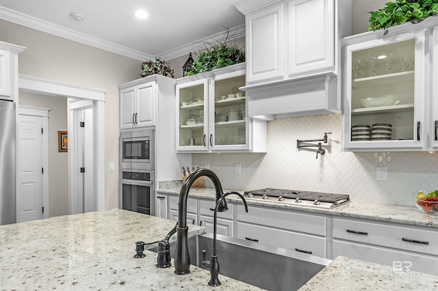 kitchen featuring white cabinetry, tasteful backsplash, glass insert cabinets, appliances with stainless steel finishes, and light stone countertops