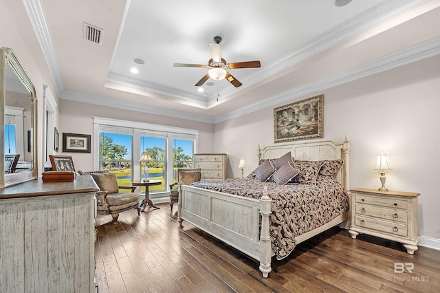 bedroom with dark wood finished floors, visible vents, ornamental molding, and a tray ceiling