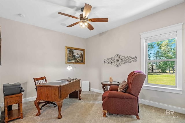 carpeted office space with a ceiling fan and baseboards