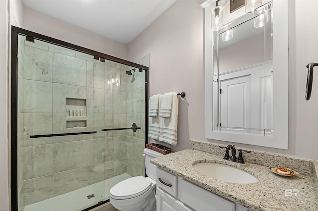 bathroom with a stall shower, toilet, and vanity