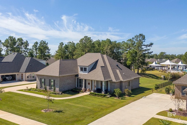 craftsman house featuring a residential view, a shingled roof, a front yard, fence, and brick siding