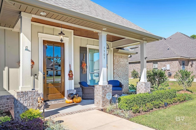 view of exterior entry featuring roof with shingles and a porch