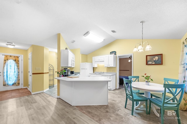 kitchen featuring pendant lighting, white appliances, vaulted ceiling, light wood-type flooring, and white cabinetry