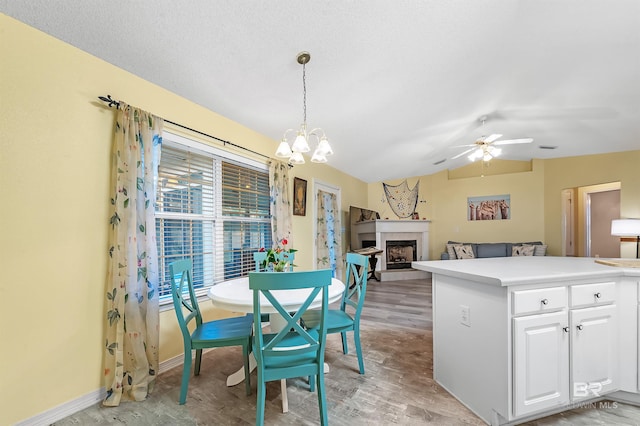 dining space with ceiling fan with notable chandelier, lofted ceiling, and light wood-type flooring