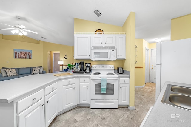 kitchen with kitchen peninsula, white appliances, white cabinets, and lofted ceiling