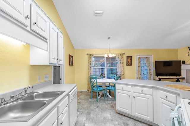 kitchen with white dishwasher, white cabinetry, hanging light fixtures, and sink