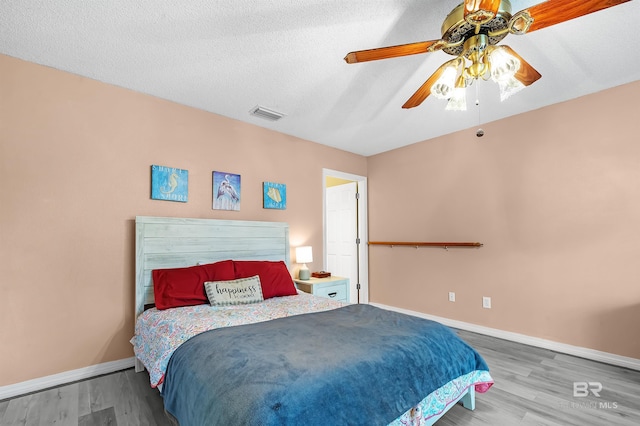 bedroom with hardwood / wood-style flooring, ceiling fan, and a textured ceiling