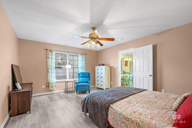 bedroom featuring ceiling fan, light wood-type flooring, and a textured ceiling