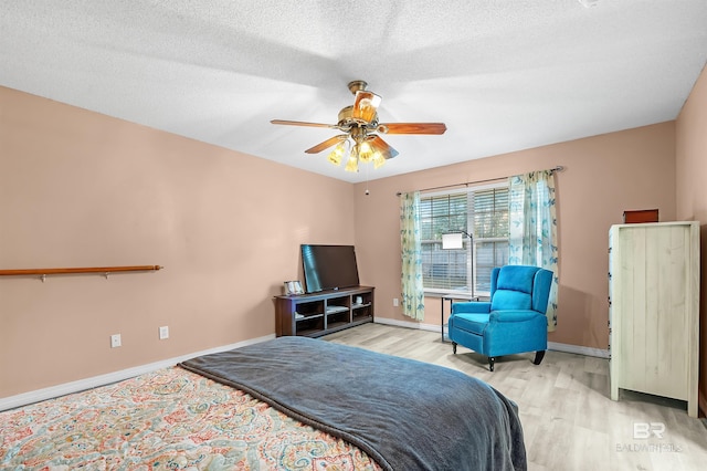 bedroom with a textured ceiling, light hardwood / wood-style floors, and ceiling fan