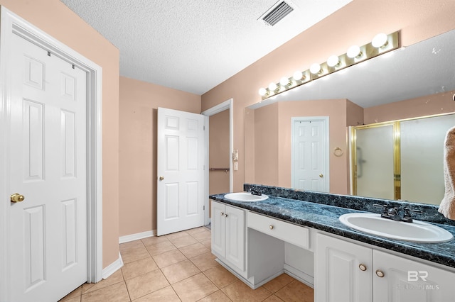 bathroom featuring tile patterned flooring, vanity, an enclosed shower, and a textured ceiling