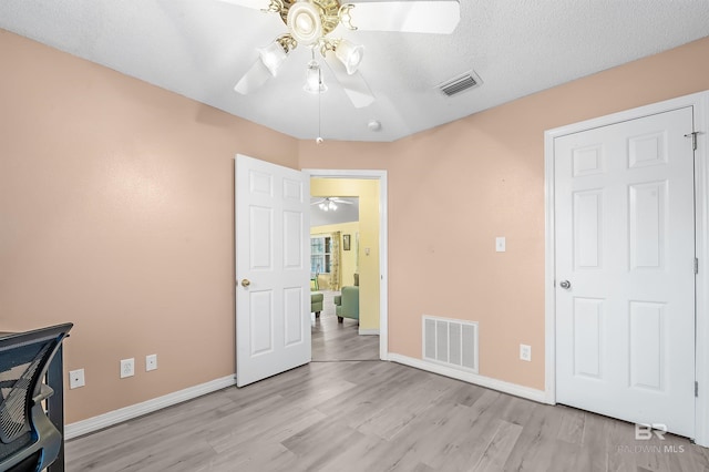 unfurnished office featuring ceiling fan, light hardwood / wood-style floors, and a textured ceiling