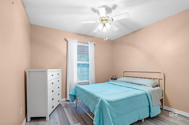 bedroom with wood-type flooring, a textured ceiling, and ceiling fan