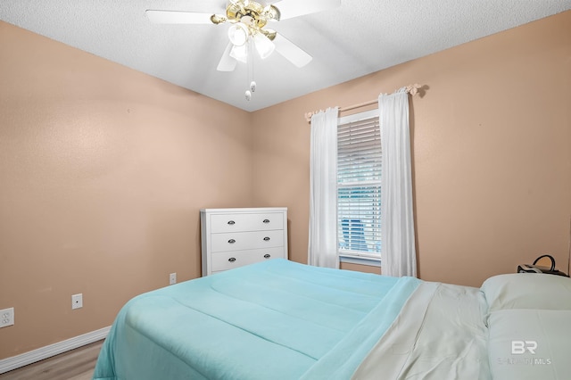 bedroom featuring ceiling fan, wood-type flooring, and a textured ceiling