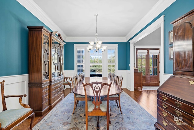 dining area with a chandelier, dark wood-style flooring, wainscoting, and crown molding