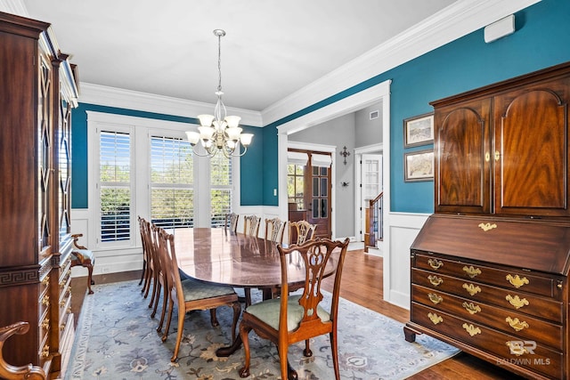 dining space featuring wainscoting, plenty of natural light, light wood-style flooring, and an inviting chandelier