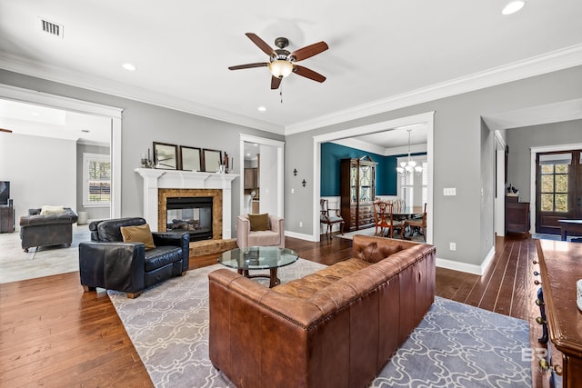 living room with baseboards, wood finished floors, visible vents, and crown molding