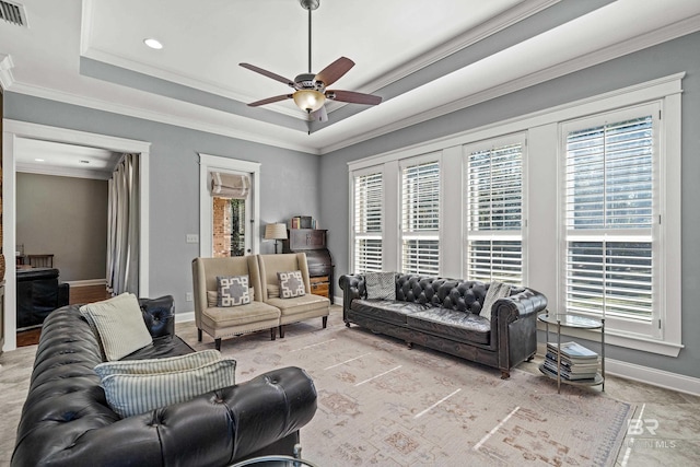 living area featuring a raised ceiling, visible vents, ornamental molding, a ceiling fan, and baseboards