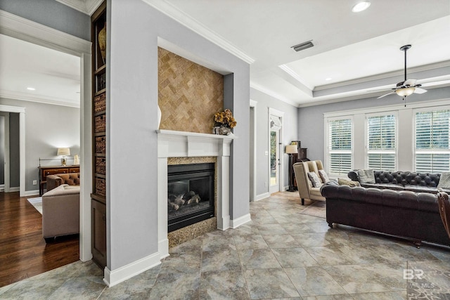 living room featuring baseboards, a premium fireplace, visible vents, and crown molding