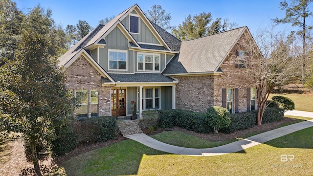 craftsman inspired home featuring board and batten siding, brick siding, a shingled roof, and a front lawn