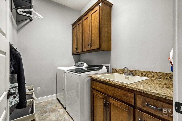 clothes washing area featuring washer and clothes dryer, a sink, cabinet space, and baseboards