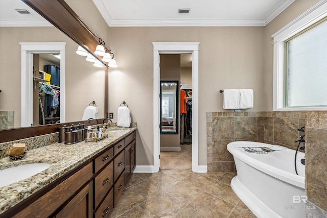 bathroom with a walk in closet, double vanity, visible vents, a sink, and a freestanding tub