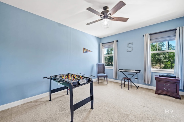 playroom with a ceiling fan, light carpet, and baseboards