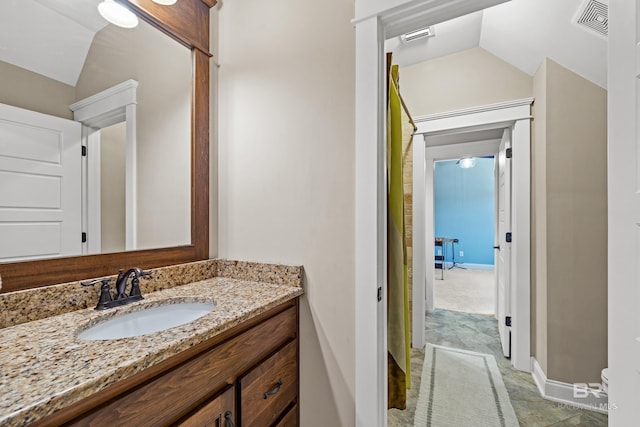 bathroom with lofted ceiling, visible vents, vanity, and baseboards