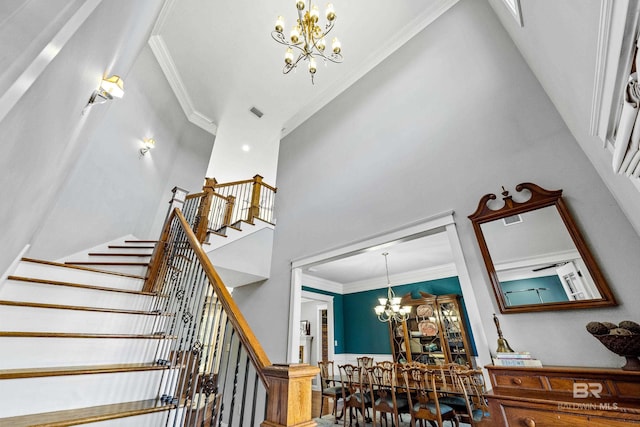 stairs featuring ornamental molding, visible vents, a notable chandelier, and a high ceiling