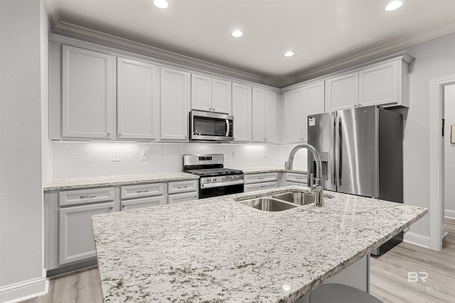 kitchen featuring light stone counters, sink, appliances with stainless steel finishes, and a kitchen island with sink