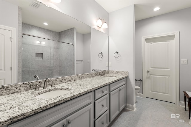 bathroom with toilet, vanity, and tiled shower