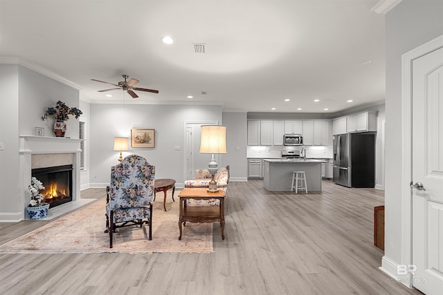 living room with ceiling fan, light hardwood / wood-style flooring, and crown molding